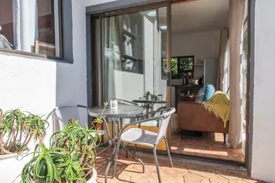 a patio with a table and chairs and plants at Apartment in Milnerton close to Woodbridge Island in Cape Town