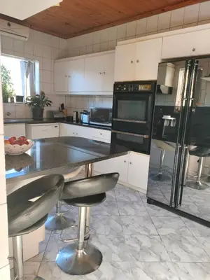 a kitchen with a black refrigerator and two stools at Near Grandwest in Cape Town
