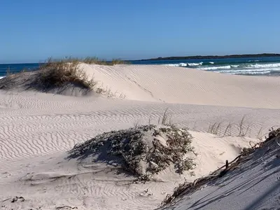 a mound of sand on a beach next to the ocean at Seaview on 2822 Happy Whale Cottage in Bettyʼs Bay