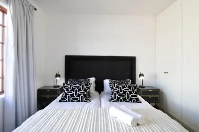 a bedroom with a bed with black and white pillows at 2 Barford Haven in Hermanus