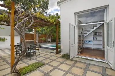 an open door of a house with a patio at Voelklip Beach Cottage in Hermanus