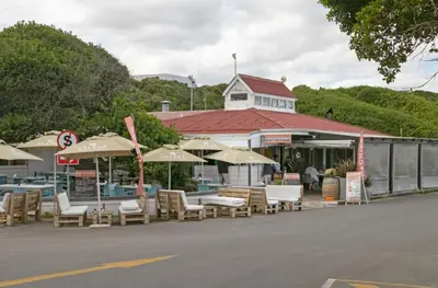 a group of chairs and umbrellas in front of a building at Voelklip Beach Cottage in Hermanus