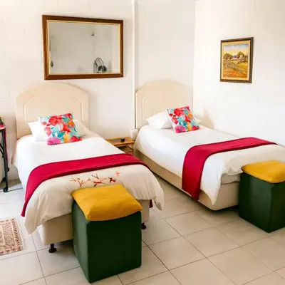 two beds in a room with two ottomans at Suzies Huis Restaurant Bed and Breakfast in Cape Town