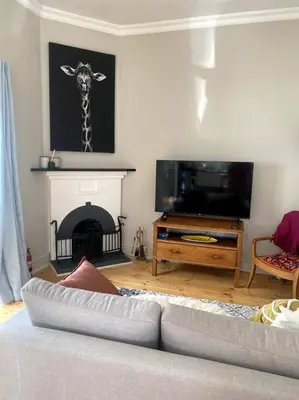 a living room with a couch and a giraffe picture on the wall at Milner Cottage: Digital Nomad Oasis in Cape Town