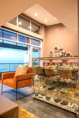 a room with a couch and a glass display case at Serviced Beach Penthouse, 100k Gemstone display, All Ensuite in Cape Town