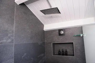 a bathroom with a shower with bottles on a wall at Oranje Meul in Paarl