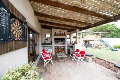 a patio with chairs and a table and a dartboard at La Haven Self Catering in Hermanus