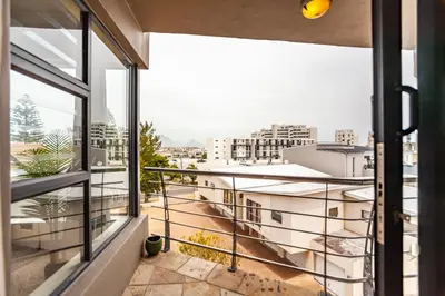 an apartment with a view of the city from a balcony at Beachfront 3rd floor 2 bedroom w communal swimming pool- B16 Blouberg in Bloubergstrand