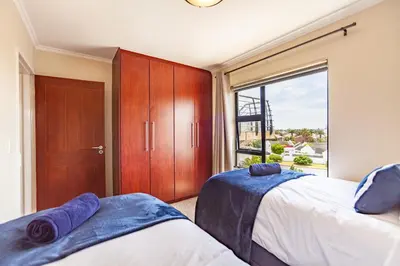 a bedroom with two beds and a large window at Beachfront 3rd floor 2 bedroom w communal swimming pool- B16 Blouberg in Bloubergstrand