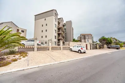 a white car parked in front of a building at Beachfront 3rd floor 2 bedroom w communal swimming pool- B16 Blouberg in Bloubergstrand