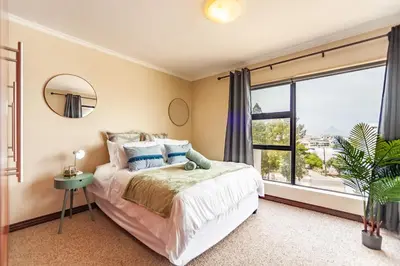 a bedroom with a bed and a large window at Beachfront 3rd floor 2 bedroom w communal swimming pool- B16 Blouberg in Bloubergstrand