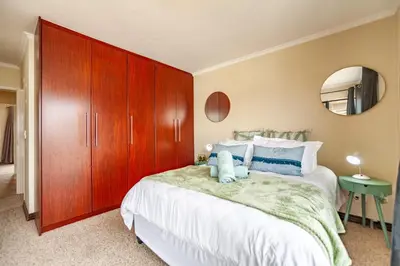 a bedroom with a large bed with a large wooden cabinet at Beachfront 3rd floor 2 bedroom w communal swimming pool- B16 Blouberg in Bloubergstrand