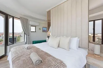 a bedroom with a large white bed with windows at 30% off Designer Penthouse - backup power - Cape Town in Cape Town