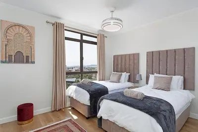 a bedroom with two beds and a large window at 30% off Designer Penthouse - backup power - Cape Town in Cape Town