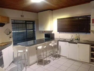 a kitchen with white cabinets and bar stools at Cape Town 5 bedroom house Belhar in Cape Town