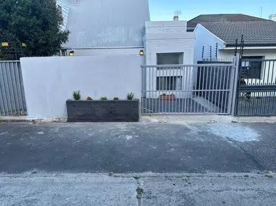 a white fence in front of a house at Lemon House Modern duplex by UCT in Cape Town