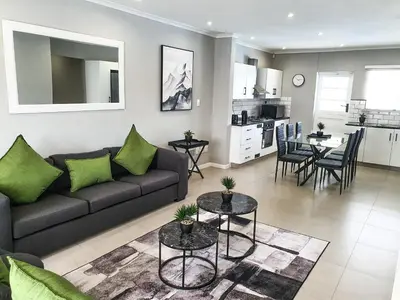 a living room and kitchen with a couch and tables at Howards Villas in Cape Town