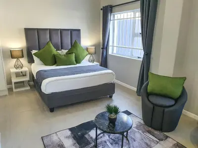 a bedroom with a king sized bed and a chair at Howards Villas in Cape Town