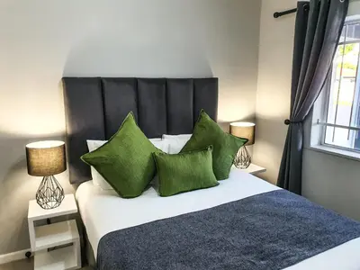 a bedroom with a large bed with green pillows at Howards Villas in Cape Town
