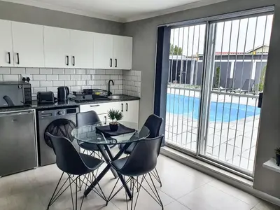 a kitchen with a table and chairs and a pool at Howards Villas in Cape Town