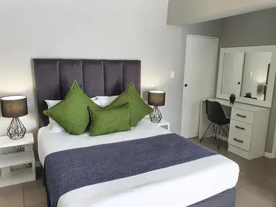 a bedroom with a large bed with green pillows at Howards Villas in Cape Town