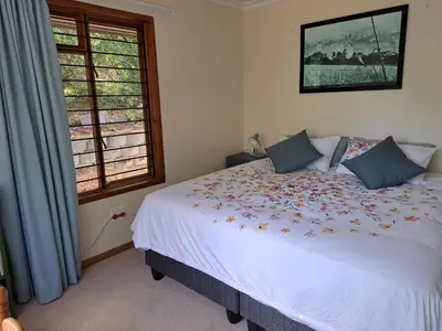 a bedroom with a white bed with flowers on it at Helderberg Cottage in Somerset West