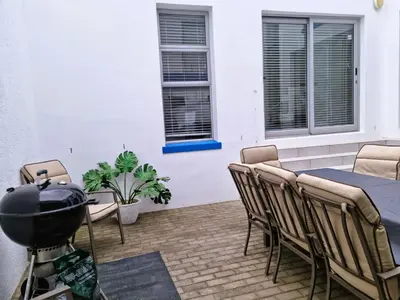 a grill on a patio with a table and chairs at 'Antilles'- 6 Bedroom Luxury Villa On The Beach, Sleeps 12 in Gordonʼs Bay
