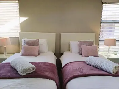 two beds sitting next to each other in a bedroom at 'Antilles'- 6 Bedroom Luxury Villa On The Beach, Sleeps 12 in Gordonʼs Bay