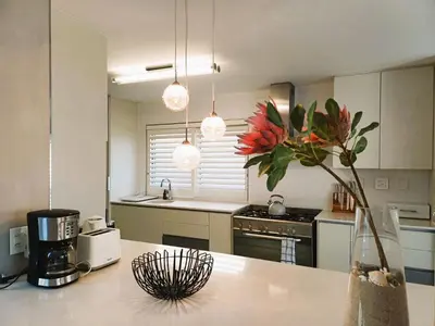 a kitchen with a vase of flowers on a counter at 'Antilles'- 6 Bedroom Luxury Villa On The Beach, Sleeps 12 in Gordonʼs Bay