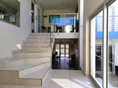 a staircase in a house with glass railing at 'Antilles'- 6 Bedroom Luxury Villa On The Beach, Sleeps 12 in Gordonʼs Bay