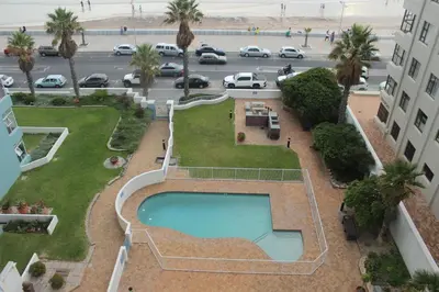 an overhead view of a swimming pool and a parking lot at Cap d Azur beachfront apartment in Strand
