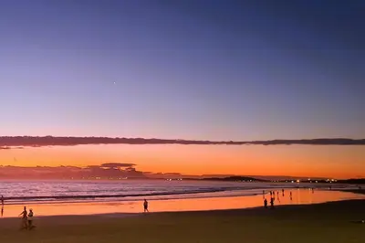a group of people standing on a beach at sunset at Cap d Azur beachfront apartment in Strand