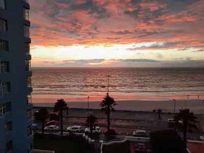 a sunset view of the ocean from a building at Cap d Azur beachfront apartment in Strand