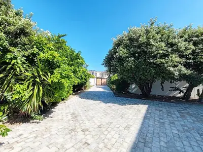 a cobblestone driveway with trees and a building at Drift Sunset Beach House in Sunset Beach