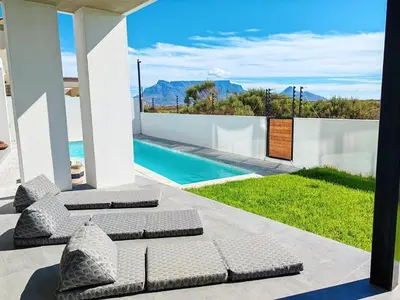 a patio with lounge chairs and a swimming pool at Drift Sunset Beach House in Sunset Beach