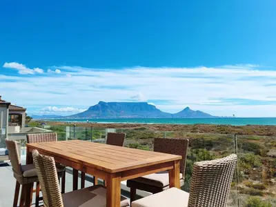 a wooden table and chairs on a balcony with a view of the ocean at Drift Sunset Beach House in Sunset Beach