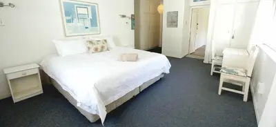 a bedroom with a large bed with white sheets at Shonalanga (The setting sun) in Hermanus
