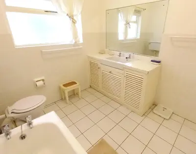 a white bathroom with a toilet and a sink at Shonalanga (The setting sun) in Hermanus