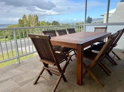 a wooden table and chairs on a balcony at Shonalanga (The setting sun) in Hermanus