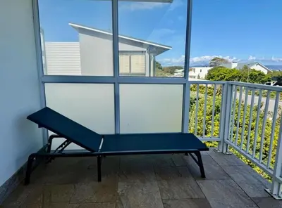 a blue bench sitting on a balcony with a window at Shonalanga (The setting sun) in Hermanus