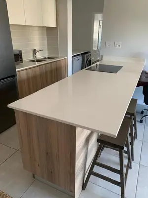 a kitchen with a white counter and chairs in it at Luxury Beach Apartment in Cape Town