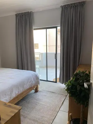 a bedroom with a bed and a sliding glass door at Luxury Beach Apartment in Cape Town