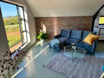 a living room with a blue couch and a brick wall at World of Horses Stables in Stellenbosch