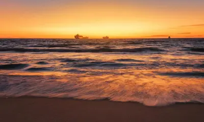 a sunset over the ocean with ships in the water at Sea Spray B306 in Bloubergstrand