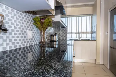 a kitchen with a vase of flowers on a counter at Sea Spray A308 in Bloubergstrand