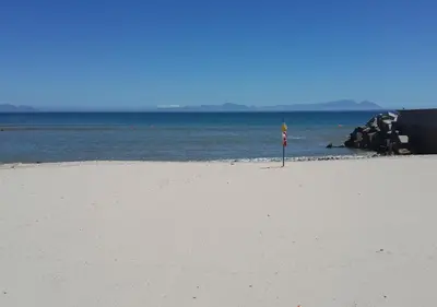 a beach with a flag in the middle of the water at First Group Cape Gordonia in Gordonʼs Bay