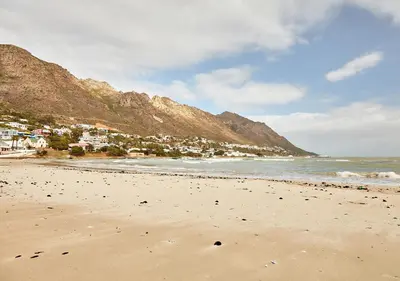 a beach with a town and mountains in the background at First Group Cape Gordonia in Gordonʼs Bay