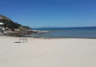 a ladder sitting on a beach near the water at First Group Cape Gordonia in Gordonʼs Bay