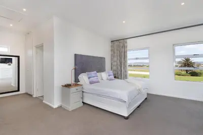 a white bedroom with a bed and a window at Sunset Westchester Villa in Cape Town