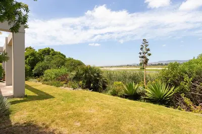 a garden with grass and plants and a house at Sunset Westchester Villa in Cape Town